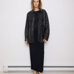Oversized vintage black leather utility jacket with flap chest pockets, worn by model over black skirt.