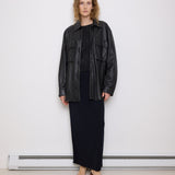 Oversized vintage black leather utility jacket with flap chest pockets, worn by model over black skirt.