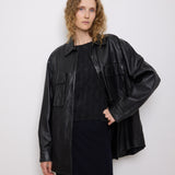Oversized vintage black leather utility jacket with flap chest pockets, worn by model over black skirt.