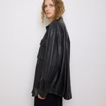 Oversized vintage black leather utility jacket with flap chest pockets, worn by model over black skirt.