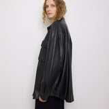 Oversized vintage black leather utility jacket with flap chest pockets, worn by model over black skirt.