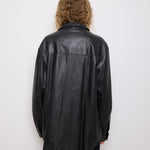 Oversized vintage black leather utility jacket with flap chest pockets, worn by model over black skirt.