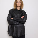 Oversized vintage black leather utility jacket with flap chest pockets, worn by model over black skirt.