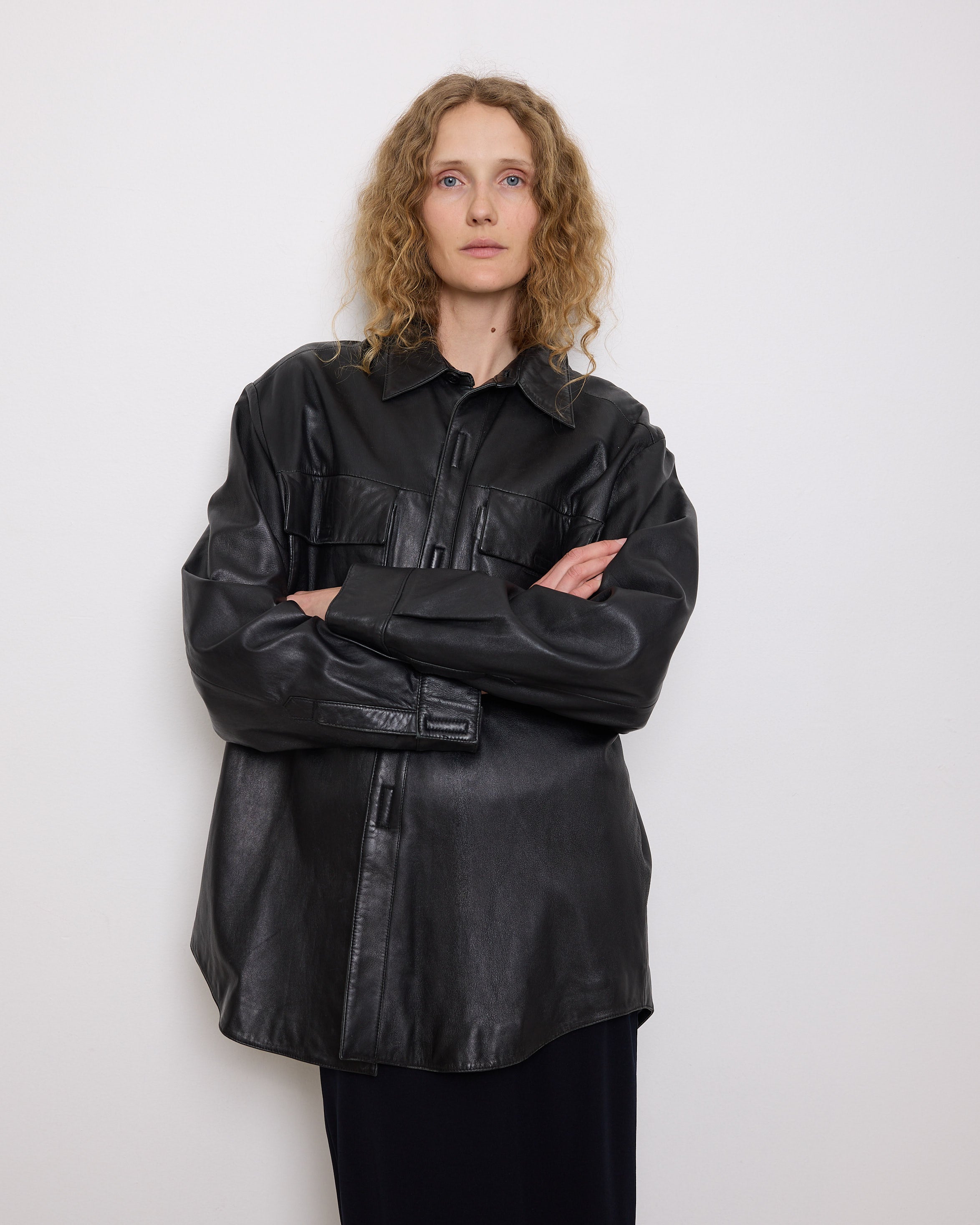 Oversized vintage black leather utility jacket with flap chest pockets, worn by model over black skirt.