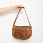 Vintage slouchy brown leather shoulder bag with gold-tone zipper and wide flat strap, shown front and back