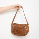 Vintage slouchy brown leather shoulder bag with gold-tone zipper and wide flat strap, shown front and back