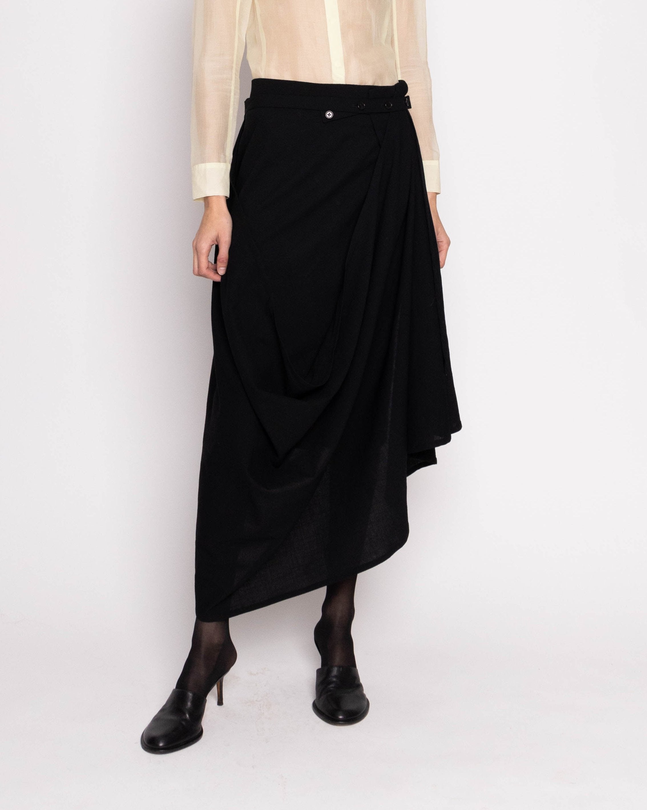 Discover the Asymmetrical Ann Demeulemeester Skirt – an ankle-length vintage masterpiece with sculptural asymmetric draping and a wrap design. With a 29-inch length, size 38 fit, and model at 5'11", embrace avant-garde vintage elegance
